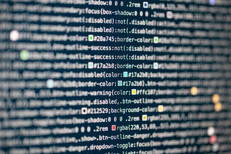 Ontwikkelaar bouwt software achter een computerscherm met code