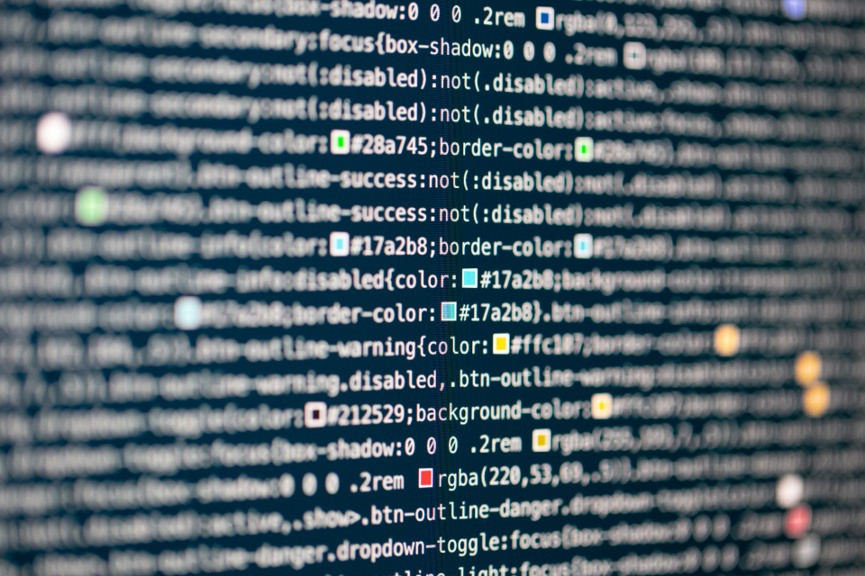 Ontwikkelaar bouwt software achter een computerscherm met code